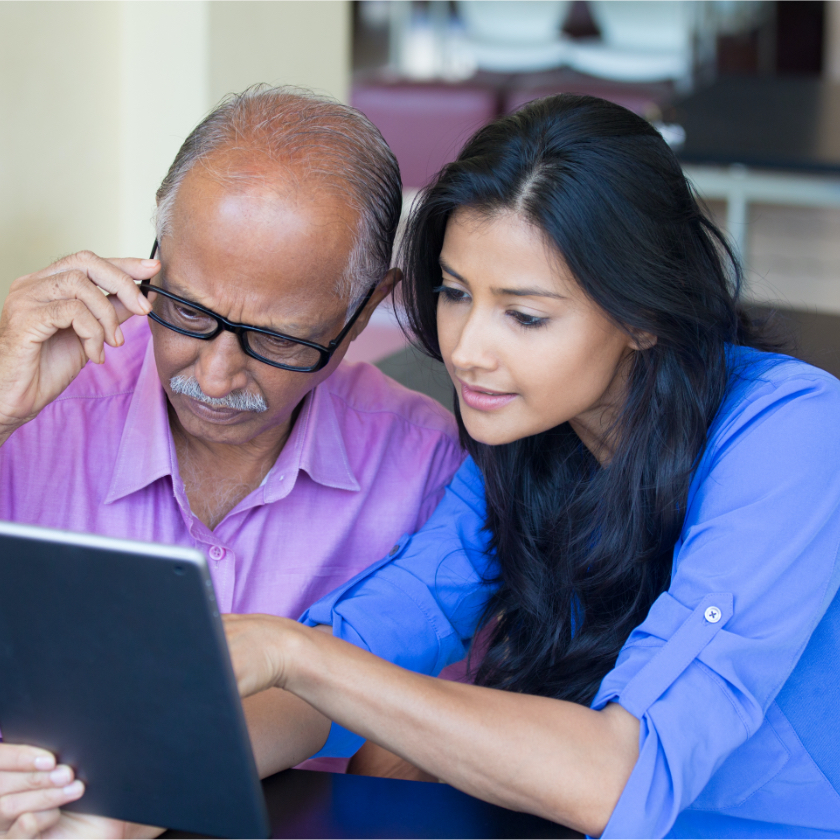 younger woman pointing to tablet while older man is looking at the screen